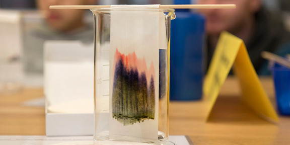 Ein Messglas in dem ein dunkel gefärbter Filter hängt.