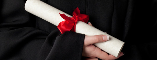 A rolled document with red bow is held by hands. 