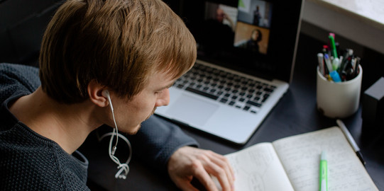 A student works with a laptop and notebook.